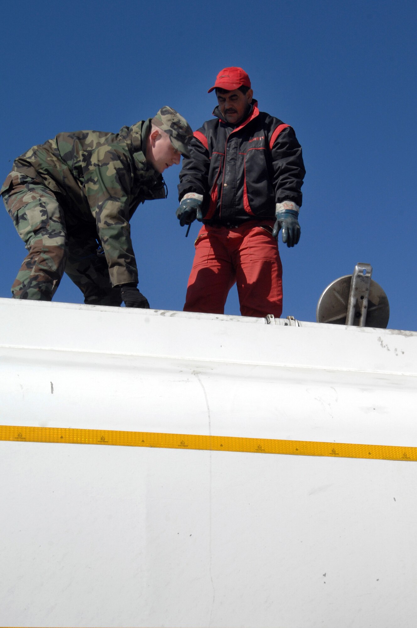 CAPMIA TURZII, Romania -- Senior Airman John Parker, 404th Expeditionary Air Base Squadron fuels equipment operator, checks the seals on a fuel truck with the driver delivering fuel here March 29, 2008. Ensuring a safe fuel supply is critical for the Air Force operations at this Romanian base.  The expeditionary unit is deployed here to augment NATO and Romanian forces in securing the airspace above the NATO Summit being held in Bucharest April 2-4.  (U.S. Air Force photo by Senior Airman Teresa M. Hawkins)