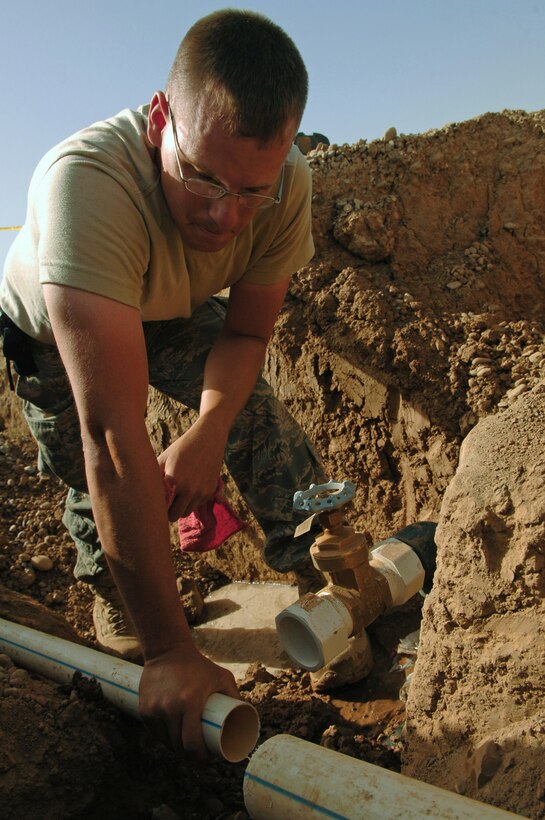 Staff Sgt. Kyle Mitchell drains stagnant water out of a water main before reattaching it to a valve March 24 at Balad Air Base, Iraq. The 332nd Civil Engineer Squadron plumbers have taken on a pipe infrastructure replacement project involving the removal of old pipes and replacing them with new, thicker gauge pipes that will bring the Air Force housing area to the next echelon of stability. The project is projected to be completed by mid-June. Sergeant Mitchell is a 332nd CES plumber deployed from Malmstrom Air Force Base, Mont. (U.S. Air Force photo/Senior Airman Julianne Showalter) 
