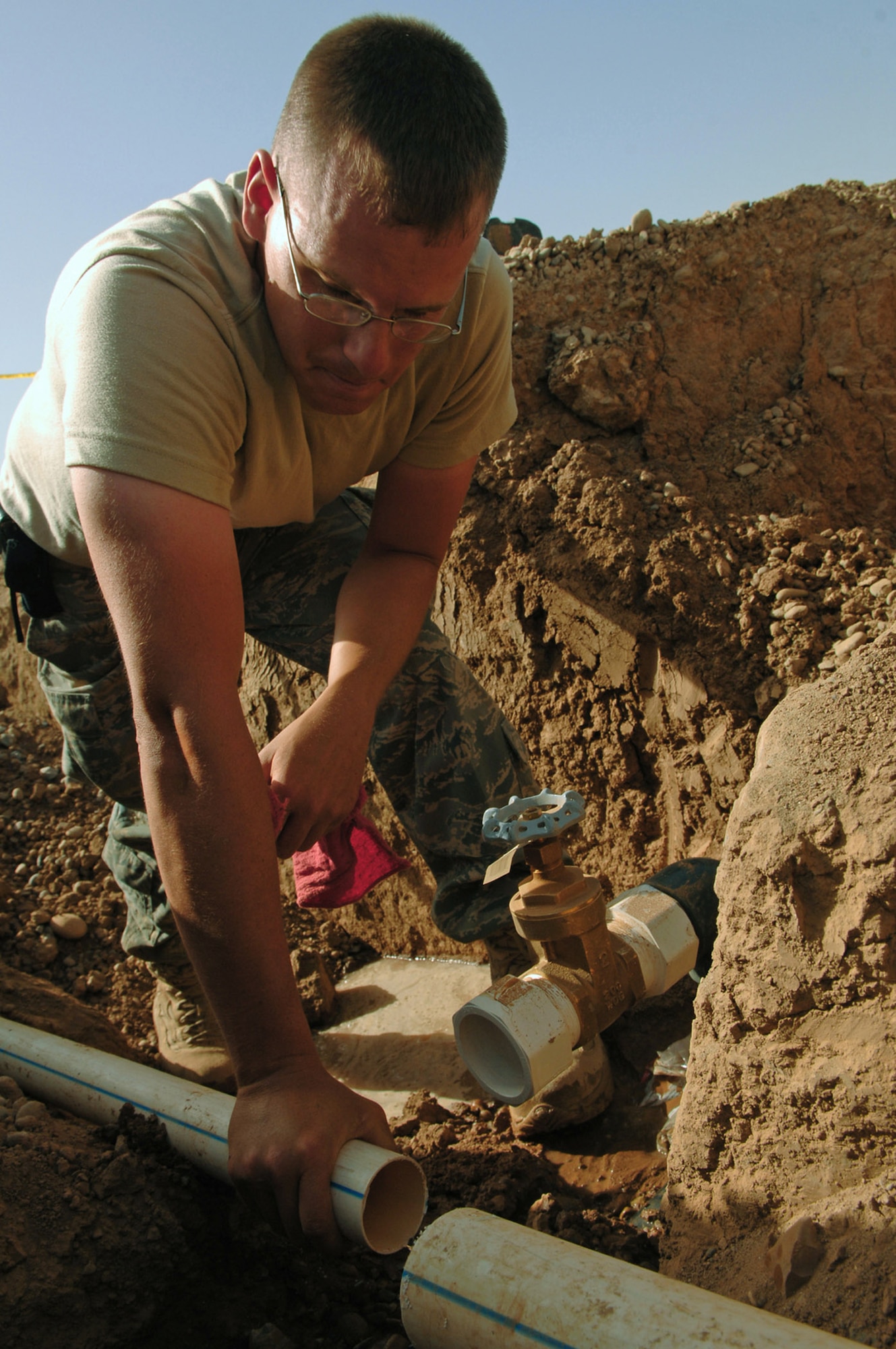 Staff Sgt. Kyle Mitchell drains stagnant water out of a water main before reattaching it to a valve March 24 at Balad Air Base, Iraq. The 332nd Civil Engineer Squadron plumbers have taken on a pipe infrastructure replacement project involving the removal of old pipes and replacing them with new, thicker gauge pipes that will bring the Air Force housing area to the next echelon of stability. The project is projected to be completed by mid-June. Sergeant Mitchell is a 332nd CES plumber deployed from Malmstrom Air Force Base, Mont. (U.S. Air Force photo/Senior Airman Julianne Showalter) 
