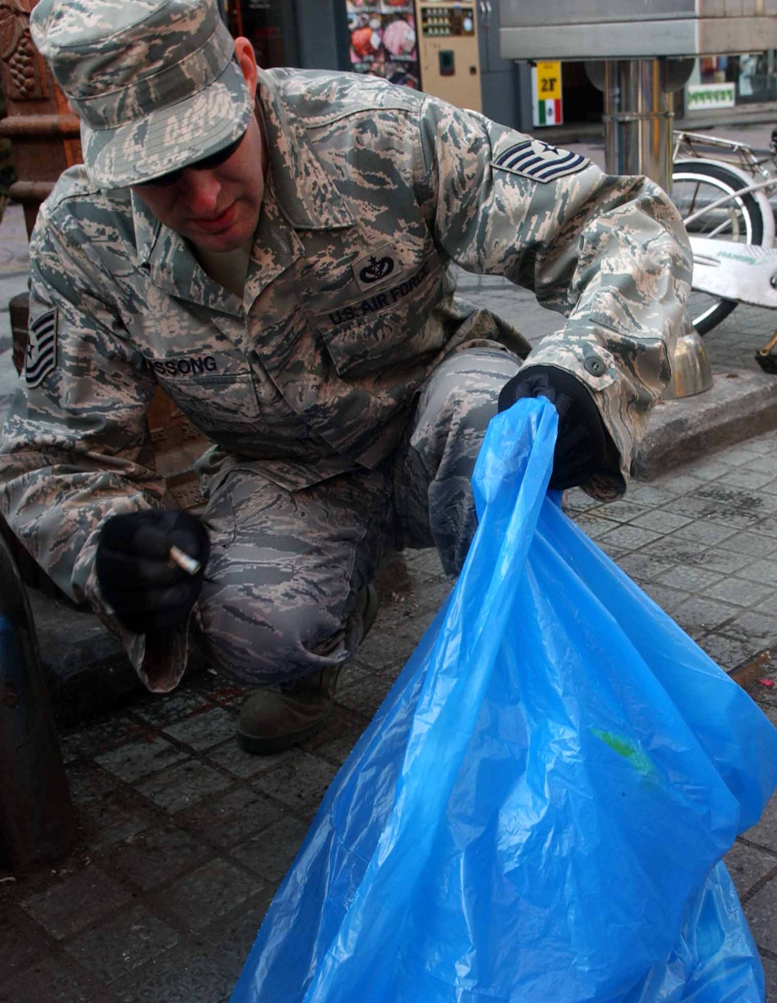 OSAN AIR BASE, Republic of Korea -- Tech. Sgt. David Hissong, 51st Civil Engineer Squadron, places debris into his garbage bag during a clean-up of the shopping mall outside the main gate April 3. The clean-up was part of Osan's Earth Day/Arbor Day celebrations. (U.S. Air Force photo/Staff Sgt. Candy Knight)