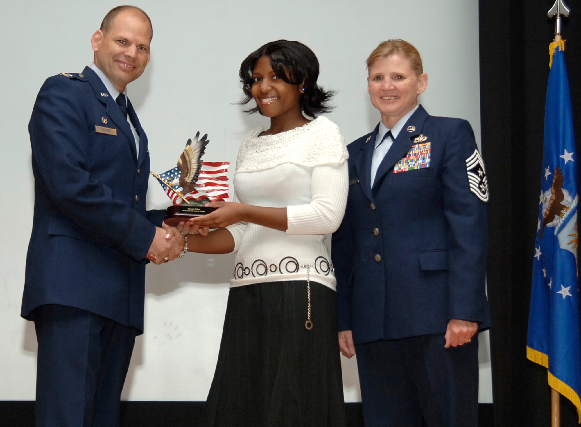 Michelle Dillard, daughter of Col. Michael Dillard, 22nd Maintenance Group commander, receives a trophy from Col. James Vechery, 22nd Air Refueling Wing commander, and Chief Master Sgt. Peggy Savage, command chief, at a wing promotion ceremony here March  28. (photo by Senior Airman Anthony Mejia)