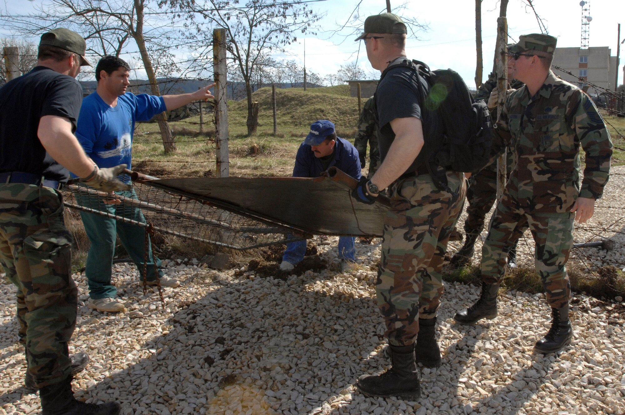 Members of the 404th Expeditionary Air Base Squadron work with Romanian nationals March 24 to remove a gate that divided the Romania base from the tent city at Campia Turzii, Romania. The deployed civil engineering team built an entire tent city in 96 hours to support U.S. operations at the air base. The Airmen are part of a team which is augmenting NATO forces in securing the airspace around Bucharest, Romania, for the NATO Summit April 2 to 4. (U.S Air Force photo/Senior Airman Teresa M. Hawkins) 