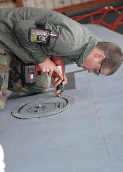 DYESS AIR FORCE BASE, Texas -- Airman 1st Class Zachary Hamman loosens screws to a hatch, April 2. One of the first things a crew chief must do is de-panel the aircraft, this is a process where all panels hiding wires or aircraft parts is removed for easier access while working. (U.S. Air Force photo Airman 1st Class Jennifer Romig)