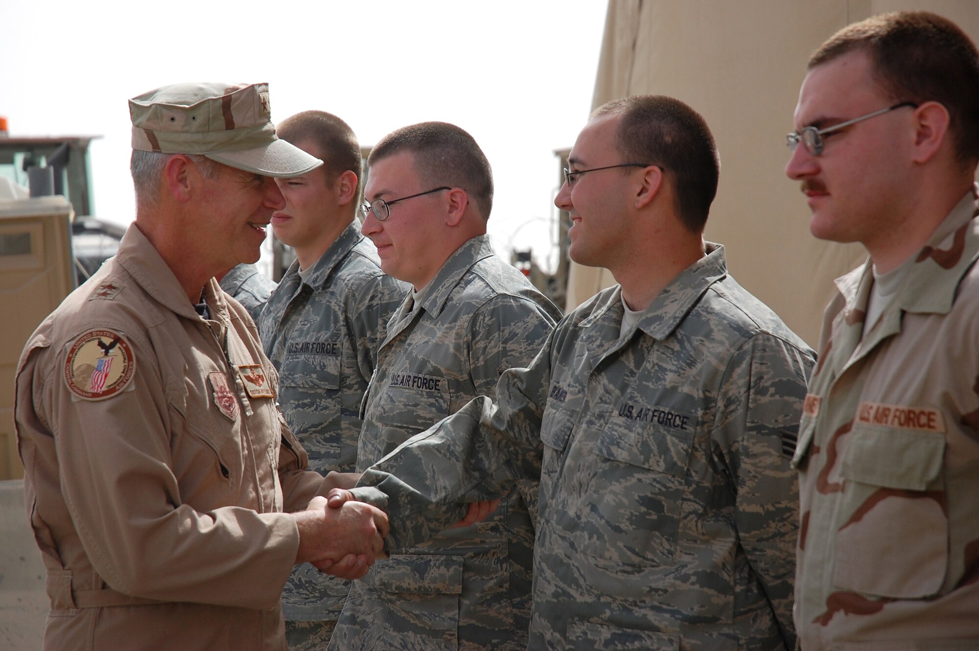 SOUTHWEST ASIA -- Major Gen. William Holland, Vice Commander, 9th Air Force, and Deputy Commander, U.S. Central Command Air Forces, Shaw Air Force Base, S.C., shakes hands with Senior Airman Andrew Baker, a member from the 386th Expeditionary Logistics Readiness Squadron's aerial port flight, during a visit to an air base in the Persian Gulf Region. General Holland visited the area of responsibility to thank the Airmen for what they do and to take back any inputs on how to better train and equip the Airmen supporting Operations Iraqi and Enduring Freedom. Airman Baker is deployed from the 436th Aerial Port Squadron, Dover Air Force Base, Del. (U.S. Air Force photo/ Staff Sgt. Patrick Dixon)