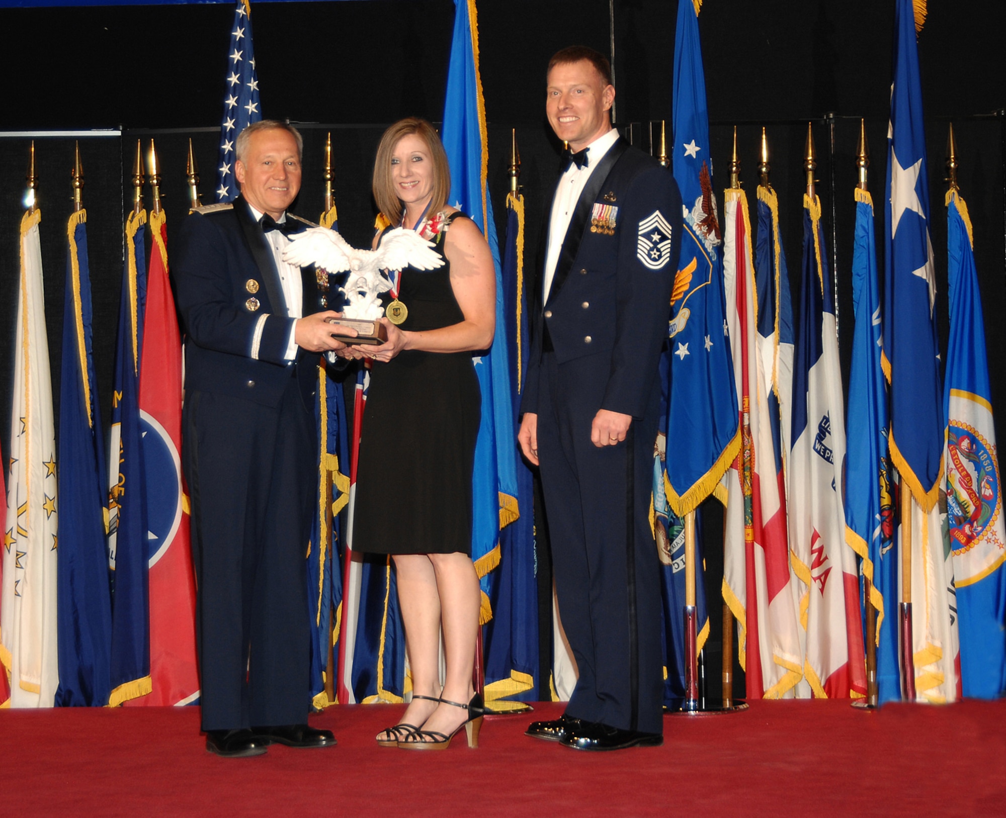 Diana Larriva poses with Gen. Bruce Carlson, commander of Air Force Materiel Command (left), and Chief Master Sgt. William C. Gurney, command chief for AFMC. She is the wife of and accepted the award on behalf of Master Sgt. David R. Larriva, AFMC’s Senior Noncommissioned Officer of the Year. Sergeant Larriva is assigned to the 95th Air Base Wing Explosive Ordnance Disposal Division, Edwards Air Force Base, Calif. He was selected from 11 nominees during a ceremony at the National Museum of the U.S. Air Force April 2. (Air Force photo by Ben Strasser)