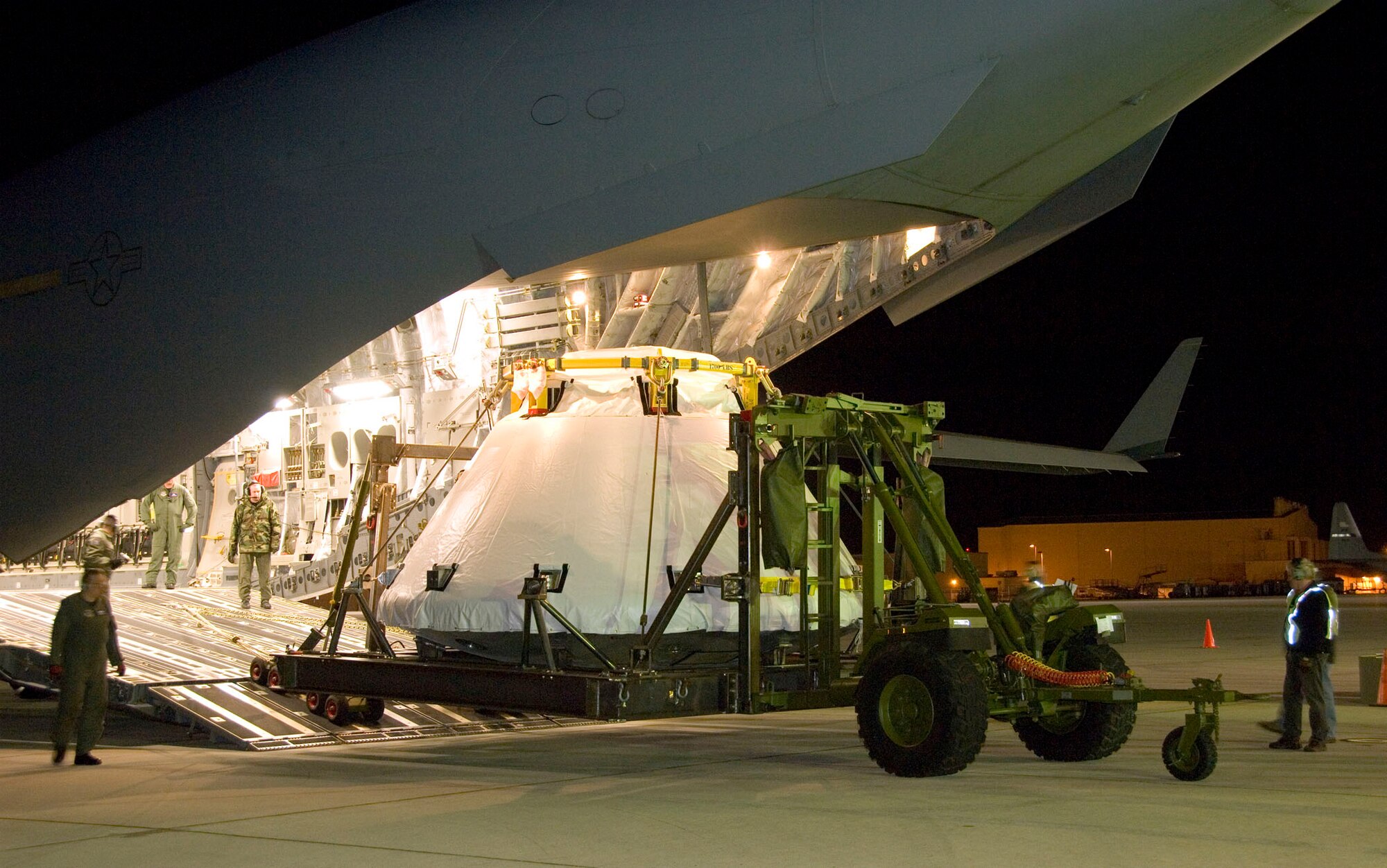 EDWARDS AIR FORCE BASE, Calif. -- Air Force loadmasters oversee the unloading of the full-scale Orion abort test crew module mockup from a C-17 Globemaster III cargo aircraft here March 28. A full-scale flight-test mockup of the Constellation program's Orion crew vehicle arrived at NASA's Dryden Flight Research Center here to undergo preparations for the first short-range flight test of the spacecraft's astronaut escape system later this year. Engineers and technicians at NASA's Langley Research Center fabricated the structure, which precisely represents the size, outer shape and mass characteristics of the Orion space capsule. (NASA photo by Tony Landis)