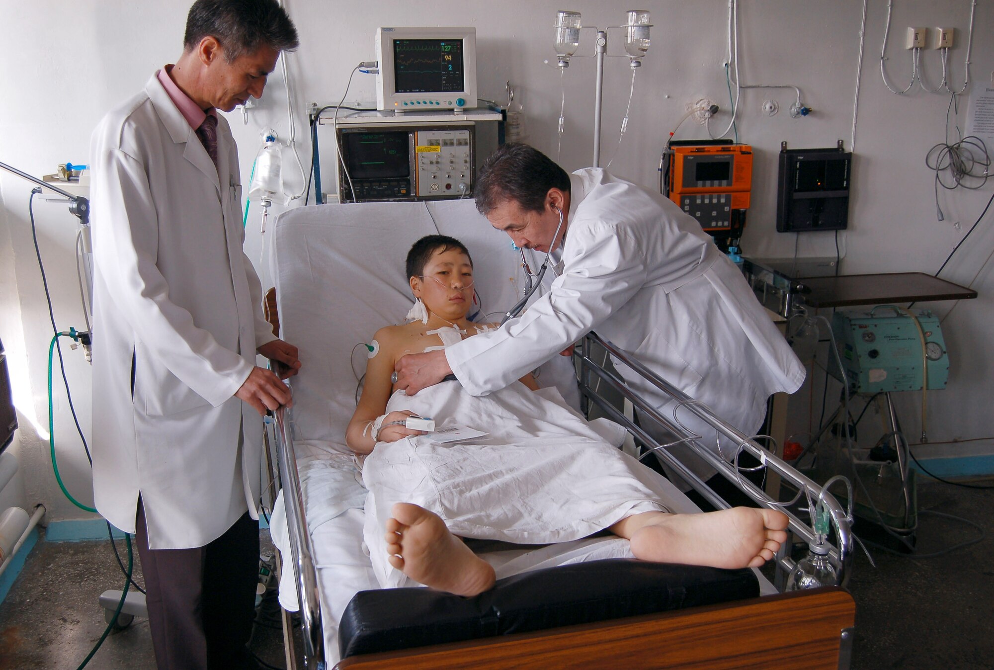 Dr. Samudin Shabyralie and Dr. Kaldarbek Abdramanov check on the Manas Air Base Outreach Society-sponsored 100th heart surgery patient, Alymbekov Amanbek, March 29 in the Children's Heart Ward in Manas, Kyrgyzstan. Dr. Shabyralie is the heart surgeon in the local Institute of Cardiac Surgery and Organ Transplantation, and Dr. Abdramanov is the director and professor of surgery. (U.S. Air Force photo/Tech. Sgt. Jerome Baysmore)