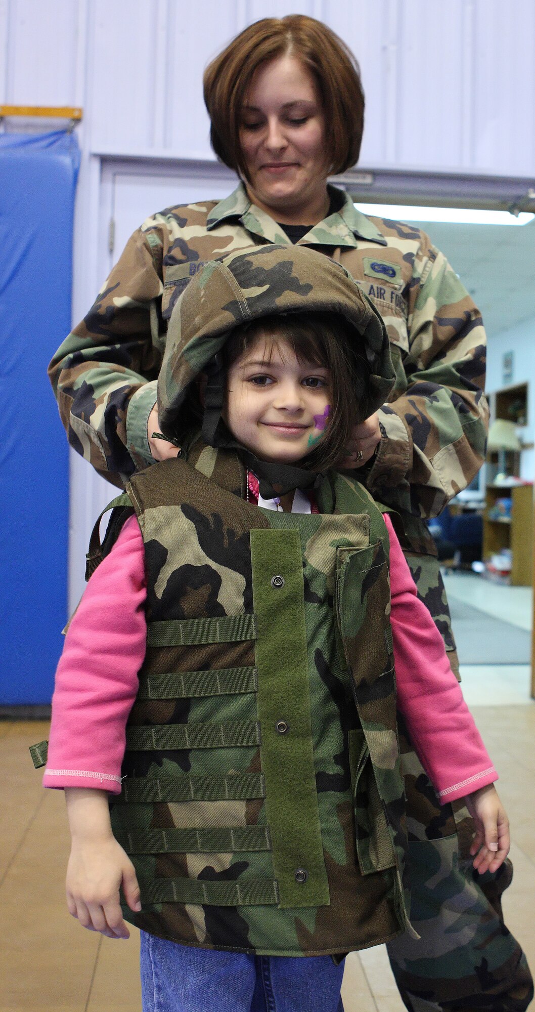 Airman 1st Class Lindsay Boisse, 436th Security Forces Squadron, buckles a battle dress flak vest and helmet on to Mila Griffith, daughter of Capt. Robert Griffith, 512th Maintenance Operations Flight commander, during the Children’s Mobility Line March 26 at the Youth Center. The Children’s Mobility Line gives children of active duty, reserve and guard Airmen the opportunity to experience what their parents go through when they deploy. (U.S. Air Force photo/ Roland Balik)
