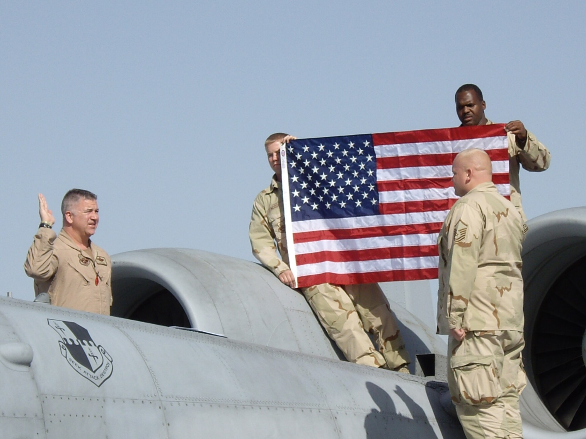 BAGRAM AIR BASE, Afghanistan – Lt. Col. Timothy Hogan re-enlists Master Sgt. Brian Downer on the wing of an A-10 as Senior Airman Calvin Woody and Staff Sgt. Victor Latson hold a flag in the background April 1, 2008. The Airmen are all deployed from Spangdahlem Air Base, Germany. (U.S. Air Force photo)