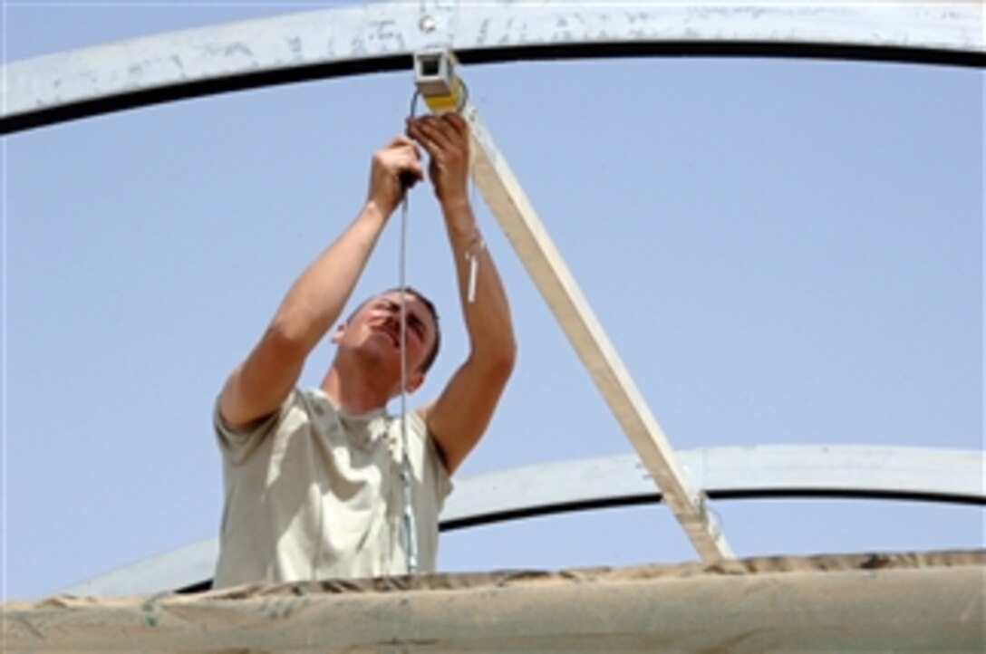 U.S. Air Force Airman 1st Class Mark Hathaway connects a cable as he constructs a tent shelter at Ali Air Base, Iraq, on March 19, 2008.  The domed tent will temporarily house an aerobic room and life fitness equipment for use by personnel on the base.  Hathaway is attached to the 407th Expeditionary Civil Engineering Squadron.  