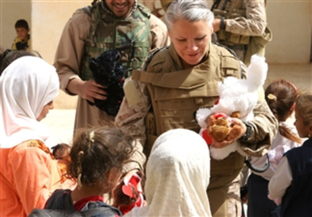 U.S. Navy Lt. Cmdr. Christina M. Williams hands out stuffed animals to school children, Al Asad, Iraq, March 31, 2008.  Williams, the medical officer for Marine Wing Support Squadron, is assigned to the 3rd Marine Aircraft Wing.