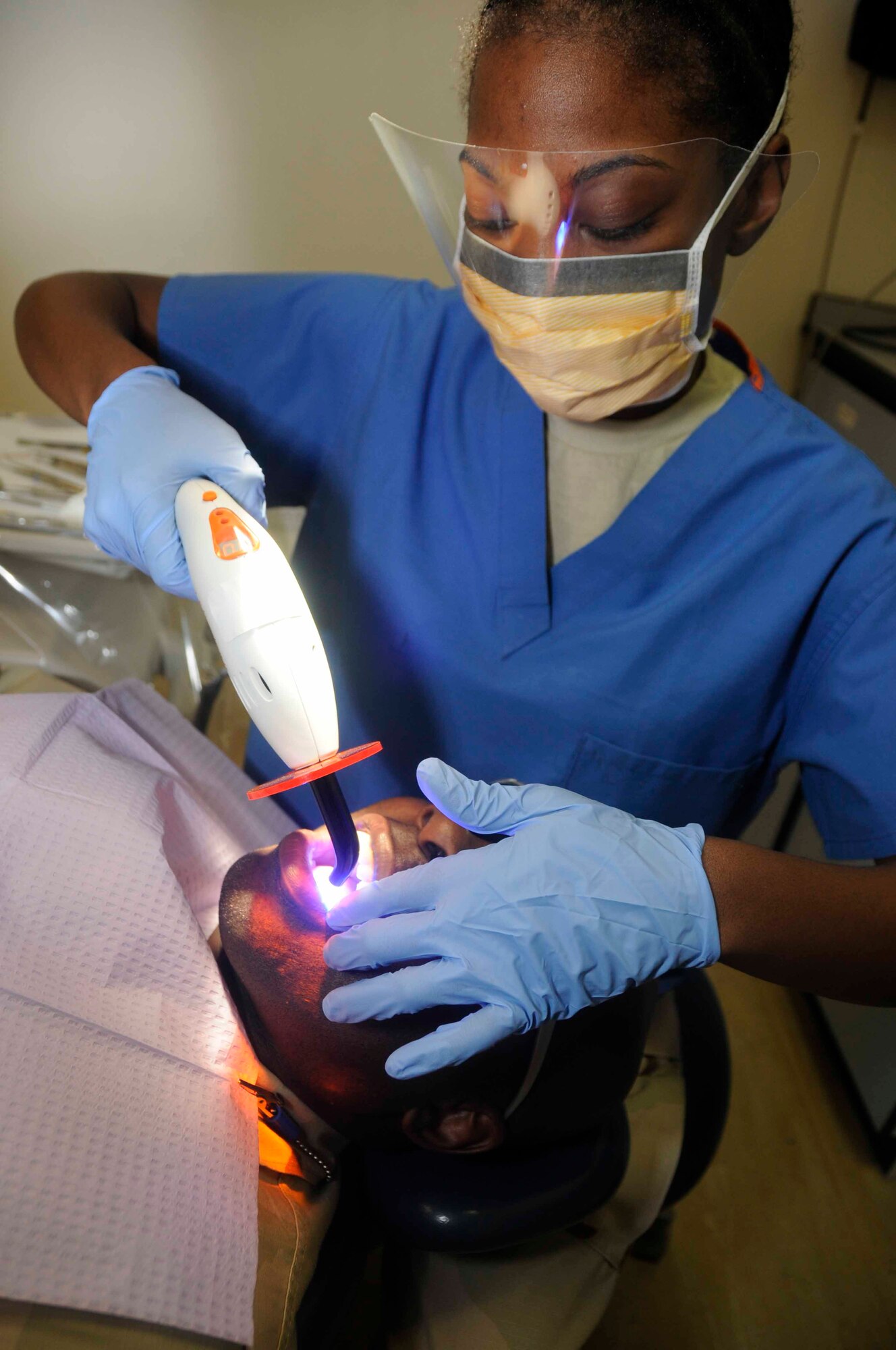 Staff Sgt. Amy Montgomery uses an infrared light to seal a filling on Tech. Sgt. Joe Watts’ tooth March 25. Sergeant Montgomery provides dental care to Air Force, sister services, and coalition members including Defense Department Civilians and contractors deployed in Southwest Asia. 