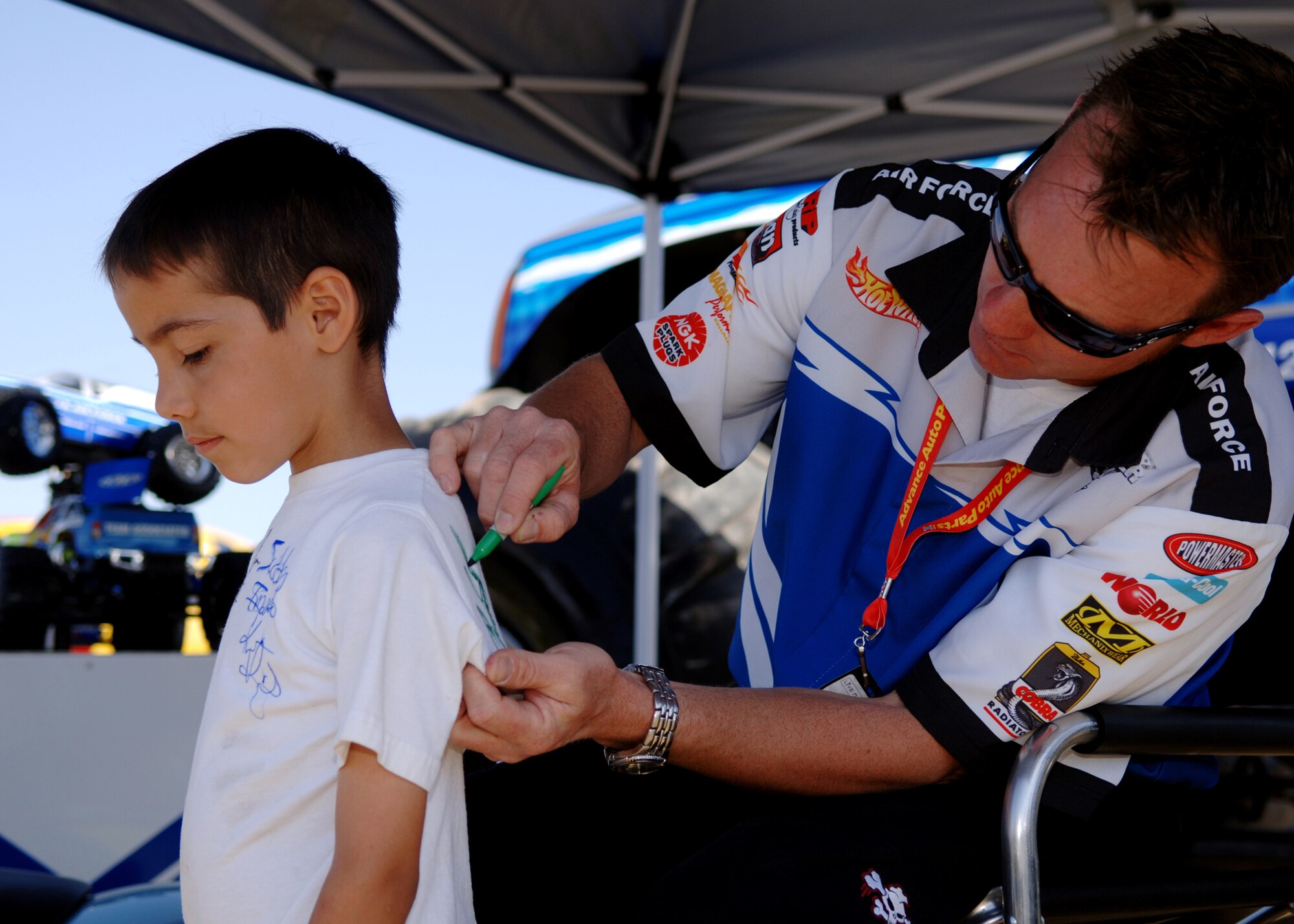 Damon Bradshaw, driver of the Air Force sponsored monster truck "Afterburner," autographs a young fan's t-shirt at the "Pit Party" prior to the Monster Jam World Finals in Las Vegas, Nev., March 29, 2008. Air Force sponsorship of Afterburner promotes Air Force awareness in monster truck fans of age to join, and in younger fans who may join the Air Force when they are older. (U.S. Air Force photo/Master Sgt. Scott Reed)