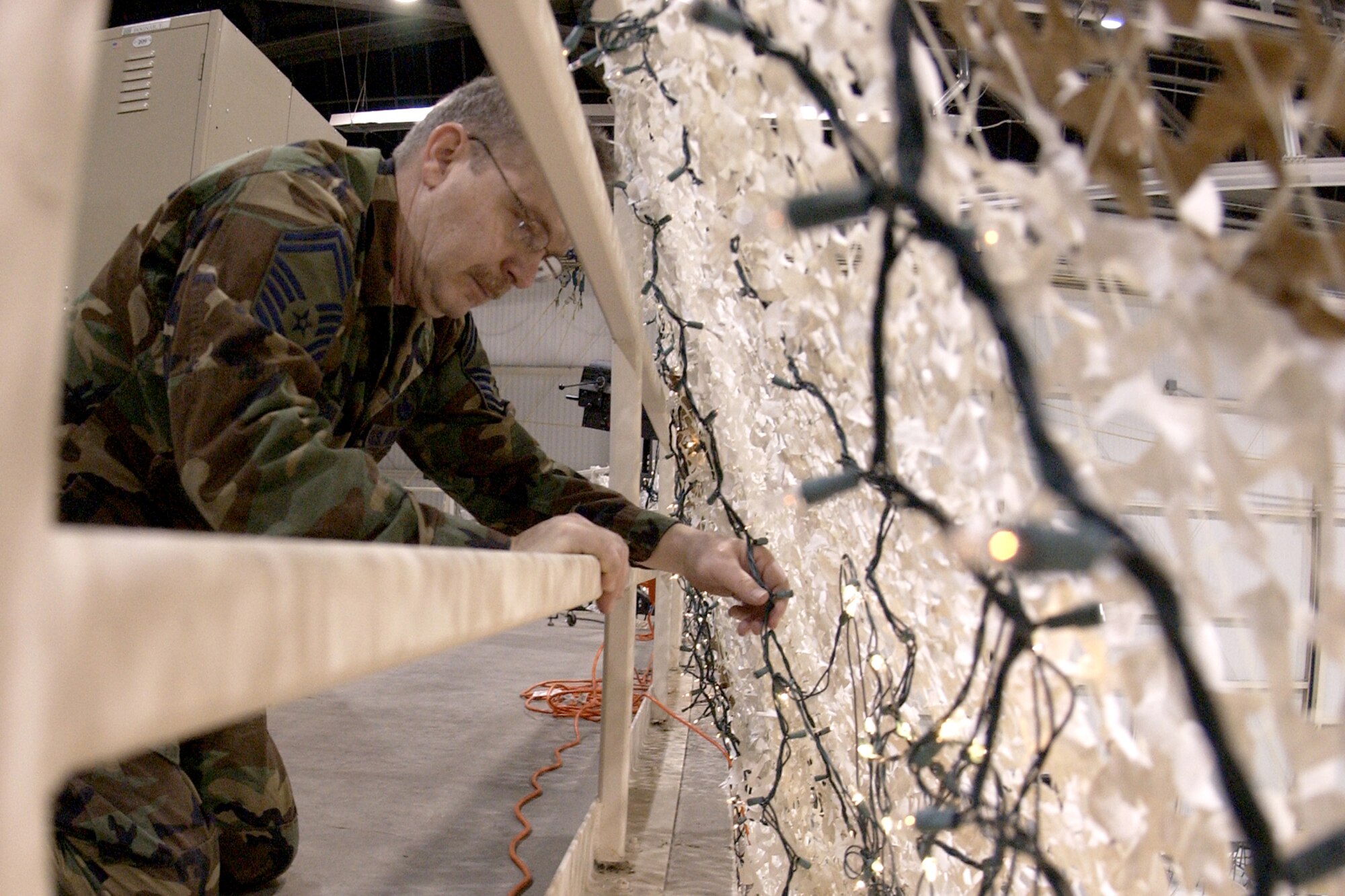 GRISSOM AIR RESERVE BASE, Ind., -- Senior Master Sgt. Bill Megnin, 434th Logistics Readiness Squadron, helps hang lights behind arctic cargo netting in Dock 1 in preparation for Grissom's Military Ball Apr. 5. Lt. Gen. John Bradley, Commander, Air Force Reserve Command, will be the guest speaker for the event. (U.S. Air Force photo/Tech. Sgt. Doug Hays)