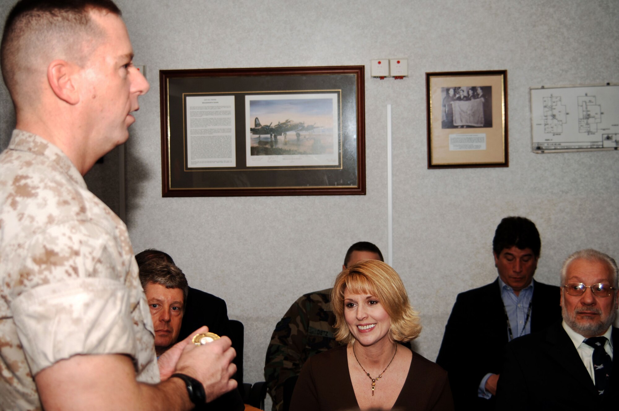 JAC Commander, Marine Corps Colonel Peter H. Devlin presents a JAC coin to Ms. Suzanne Wilson in recognition of her participation in a ceremony where the JAC officially received the records of the 7,336 members of the 303rd Bomb Group  who served at Molesworth during World War II.  To Ms. Wilson's left is Mr. Robin Beeby, U.K. representative of the Bomb Group.  The records were researched and compiled by Ms. Wilson's father, former 303rd BG B-17G pilot Lt. Col Edgar Miller.  (U. S. Air Force Photo by Staff Sgt. Jocelyn L. Rich)