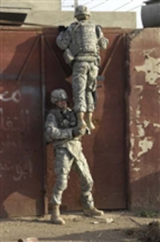 U.S. Army 1st Sgt. Shane Chapman gives another soldier a boost in order to see over a door for possible threats during a cordon and search mission in Al Sinaa, Iraq, on April 1, 2008.  The soldiers are from 1st Battalion, 8th Infantry Regiment, 3rd Brigade Combat Team, 4th Infantry Division.  