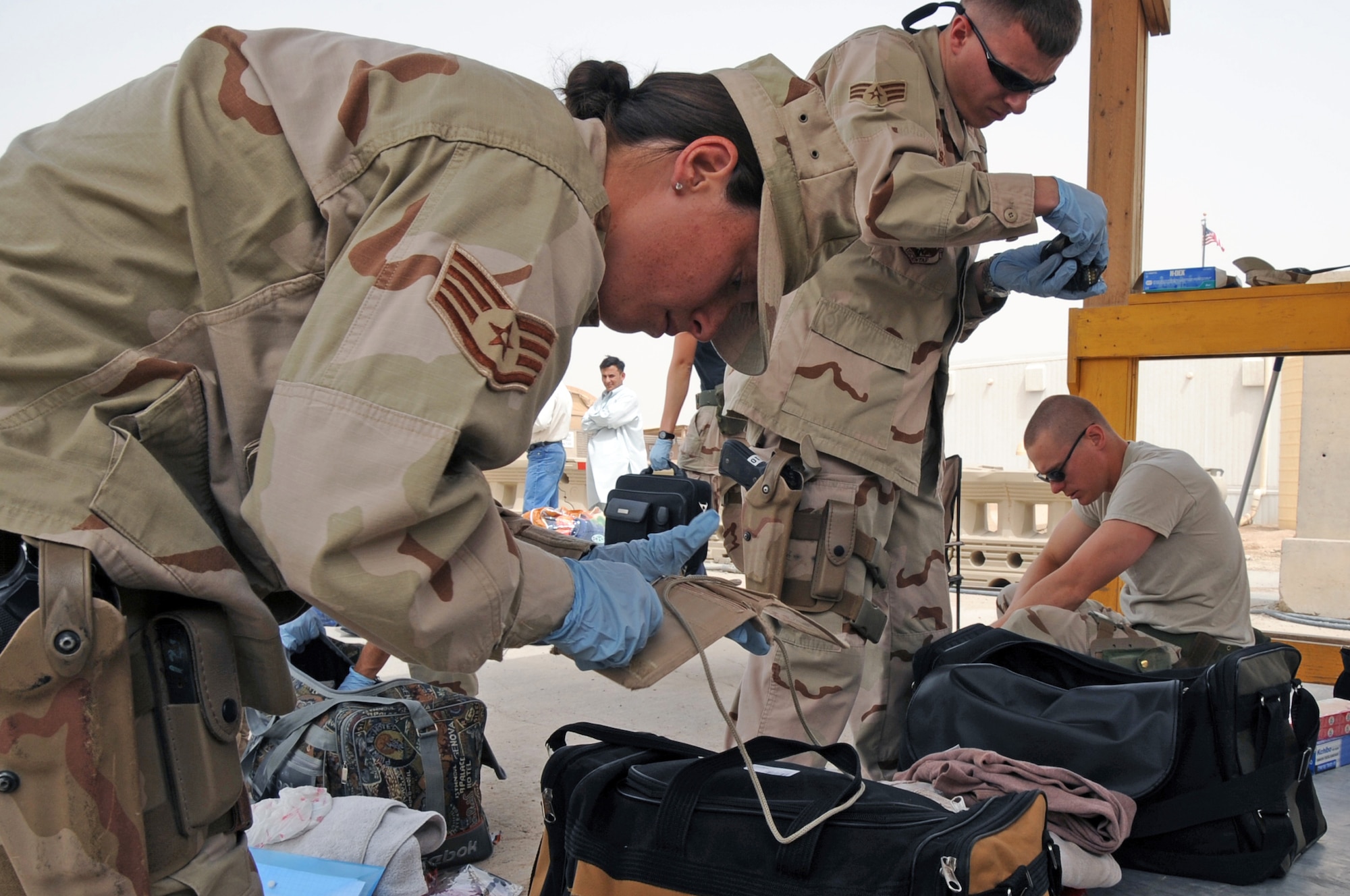ALI BASE, Iraq -- Staff Sgt. Valarie Noel, Senior Airman Ricardo Visconti and Mark Hurban, 407th Expeditionary Security Forces Squadron Force Protection Airmen,  inspect personal bags of third country national arriving for work here April 5.  The Force Protection Airmen have to inspect every person and bag they carry prior to allowing them entry onto the base.  Sergeant Noel is deployed from Hickham AFB, Hawaii and Airman Visconti and Hurban are deployed from Spangdahlem AB, Germany.  (U.S. Air Force photo/Tech. Sgt. Sabrina Johnson)
