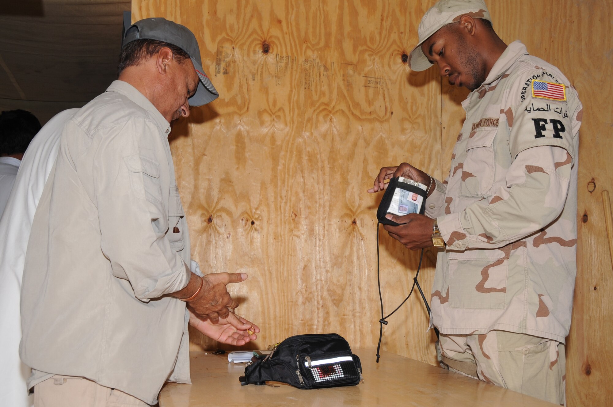 ALI BASE, Iraq -- Airman 1st Class David Ward, 407th Expeditionary Security Forces Squadron Force Protection Airman,  inspects personal belongings of a third country national arriving for work here April 5.  The Force Protection Airmen have to inspect every person and bag they carry prior to allowing them entry onto the base.  Airman Ward is deployed from Spangdahlem AB, Germany.  (U.S. Air Force photo/Tech. Sgt. Sabrina Johnson)