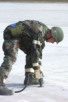 Staff Sgt. Phillip Sobers, a structures journeyman with the 911th Airlift Wing's Civil Engineering Squadron, secures the fiberglass matting during the rapid runway repair at the Air Force's Silver Flag exercise, held Feb. 4 - 8, at Tyndall AFB, Fla. The matting is used to cover craters after a runway has been bombed. (U.S. Air Force Reserve photo/Staff Sgt. Roberto Modelo)
