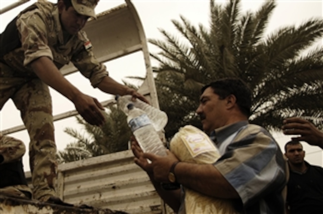 An Iraqi army soldier hands out bottled water during a humanitarian assistance mission in Baghdad, Iraq, April 5, 2008