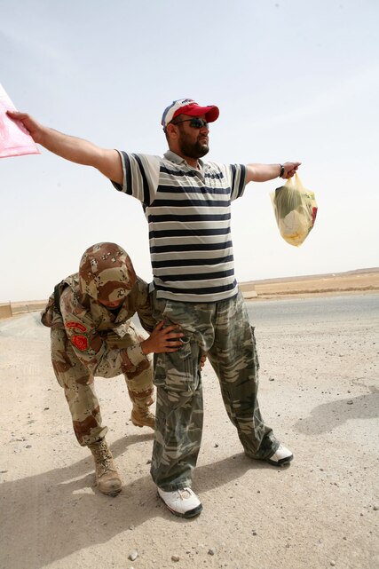 Iraqi Pvt. Kalieph Qayes, military policeman with Military in Transition Team 0720, 7th Iraqi Army Division, searches an Iraqi national before coming aboard Al-Asad Air Base April 6. All local national coming on base are subject to a search by the Iraqi soldiers manning the gate.