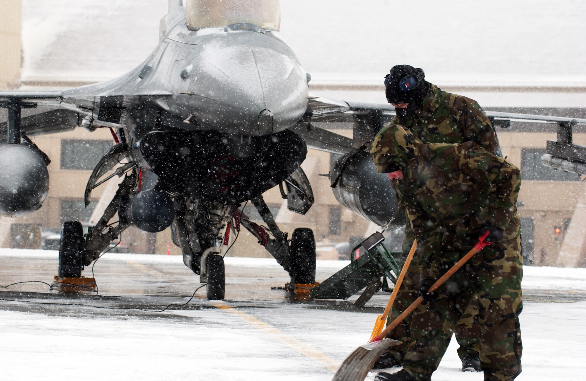 Senior Airmen Jason Thomas, front, and Joseph Robinson remove snow from the tarmac to clear a path to an F-16 Fighting Falcon for the first official day of Red Flag-Alaska 08-2 April 7 at Eielson Air Force Base, Alaska. Snow removal vehicles cannot clear snow withing 15 feet of an aircraft so maintainers shovel by hand. They are assigned to the 51st Aircraft Maintenance Squadron Osan Air Base, Korea. (U.S. Air Force Photo/Airman 1st Class Jonathan Snyder)
