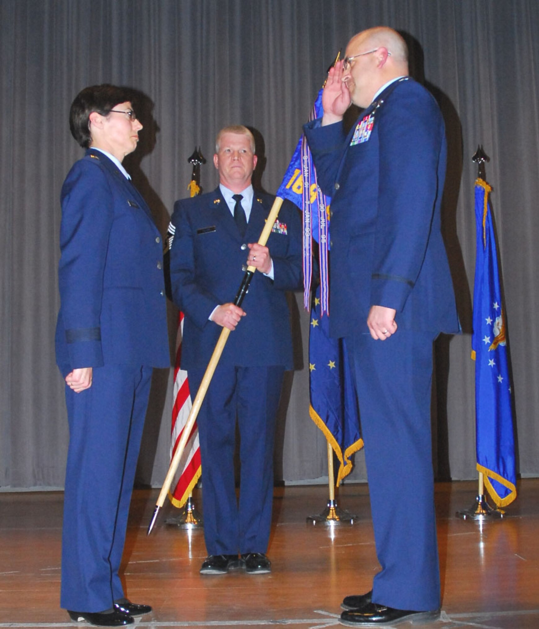 Brig. Gen. Deborah McManus, commander of the Alaska Air National Guard receives a salute from Col. Donald ?Scott? Wenke April 5 at the base theater while 168th Air Refueling Wing Command Chief Master Sgt. Stephen Fuller holds the unit guideon.  The passing of the guideon from one commander to the next is a military tradition which symbolizes the changing of command. (U.S. Air Force photo by Capt. Guy Hayes, DMVA Public Affairs)