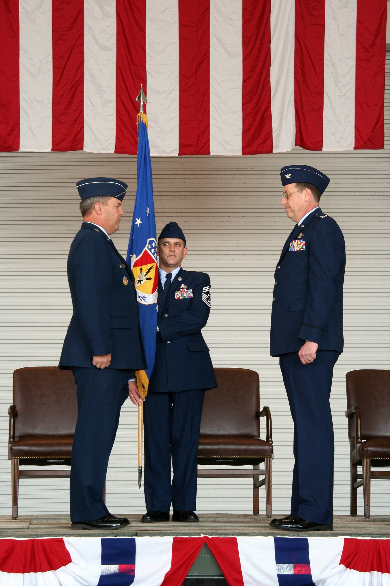 WRIGHT-PATTERSON AFB, Ohio - Maj. Gen. Robert Duignan prepares to present the 445th Airlift Wing flag to incoming Commander Col. Stephen Goeman at the wing's Change of Command Ceremony April 6, 2008.  The flag is held by Command Chief Aaron Mouser (center).  The wing said goodbye to Brig. Gen Bruce E. Davis as he relinquished command and welcomed the incoming commander, Col. Stephen D. Goeman. The ceremony took place in the wings new Fuel System Maintenance Hangar with a massive C-5 as the backdrop. (U.S. Air Force photo/Maj. Jose Cardenas)