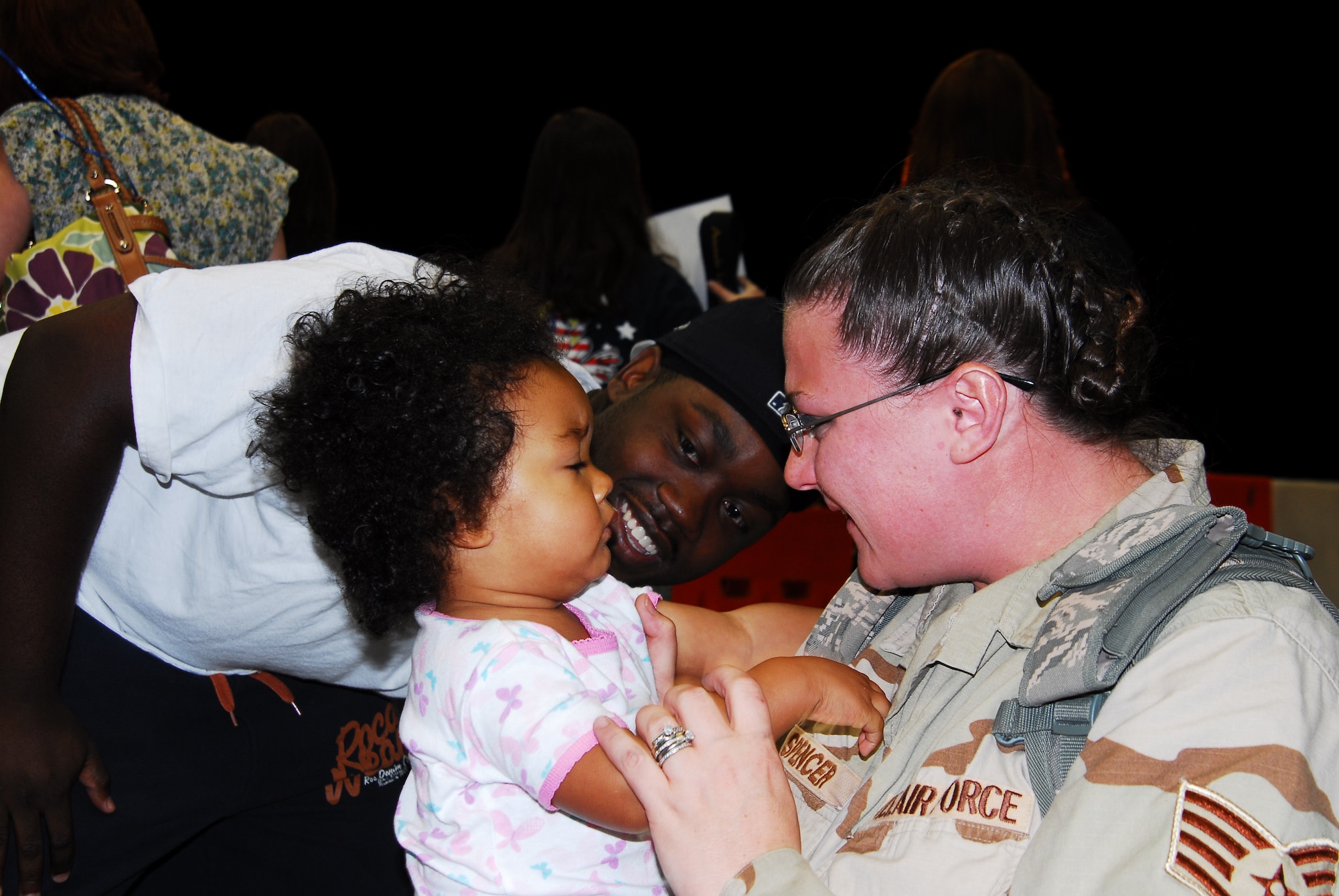 Staff Sgt. Danielle Spencer, 1st Special Operations Equipment Maintenance Squadron, reunites with her daughter Jazzmin as her husband, Staff Sgt. Derrick Spencer, 1st Special Operations Wing, looks on April 7 during the Operation Homecoming ceremony. Families, friends and coworkers piled into the 15th Aircraft Maintenance Unit hangar at 5 a.m. to greet Airmen as they returned from deployments to Southwest Asia. (U.S. Air Force photo/Senior Airman Sheila deVera)