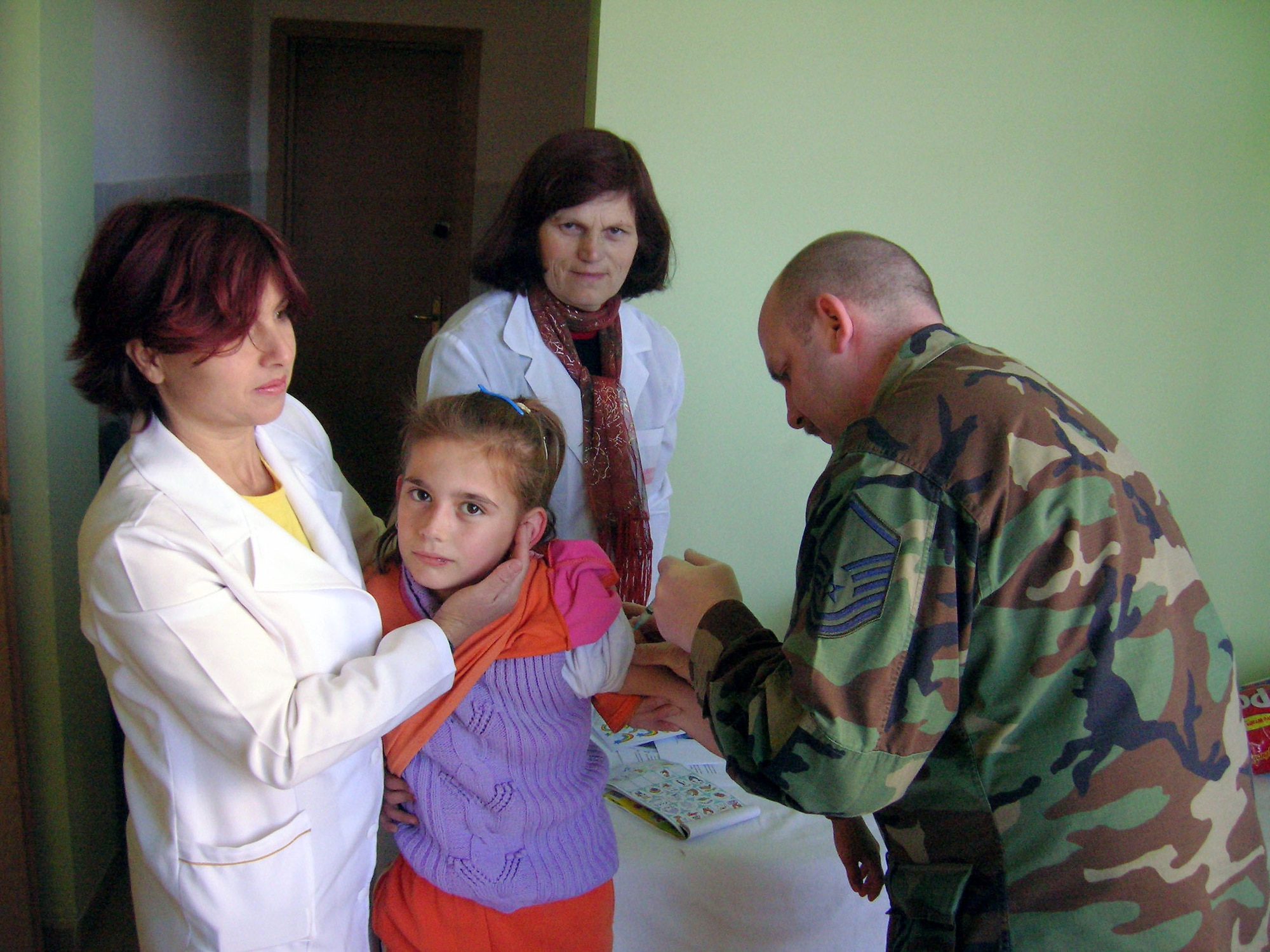Master Sgt. James Welch immunizes a girl as Albanian nurses provide assistance in February in Albania. Sergeant Welch, along with four other 109th Airlift Wing medics from the Stratton Air National Guard Base in New York, administered 1,000 Hepatitis A shots during a humanitarian mission with the New Jersey National Guard. (Courtesy photo) 
