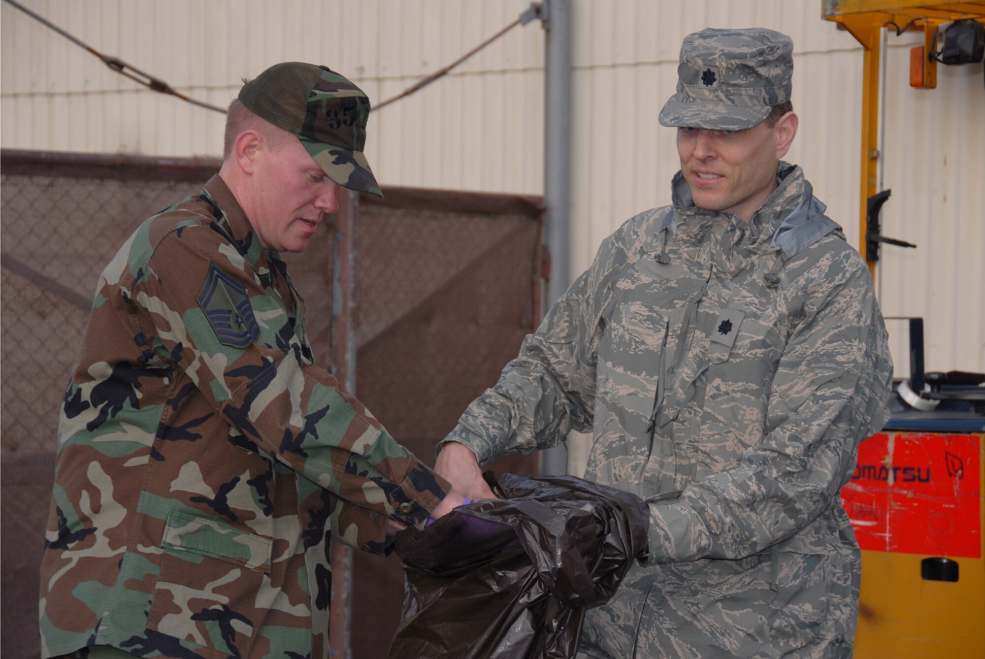 MISAWA AIR BASE, Japan --  Master Sgt. Randall Wehrung, 35th Dental Squadron, disposes of trash found on the ground as Lt. Col. Colin Smyth, 35th Medical Support Squadron commander, holds the bag here, Apr. 3, 2008.  Squadrons and groups worked together during the week to perform the yearly base clean up.  (U.S. Air Force photo by Senior Airman Laura R. McFarlane)