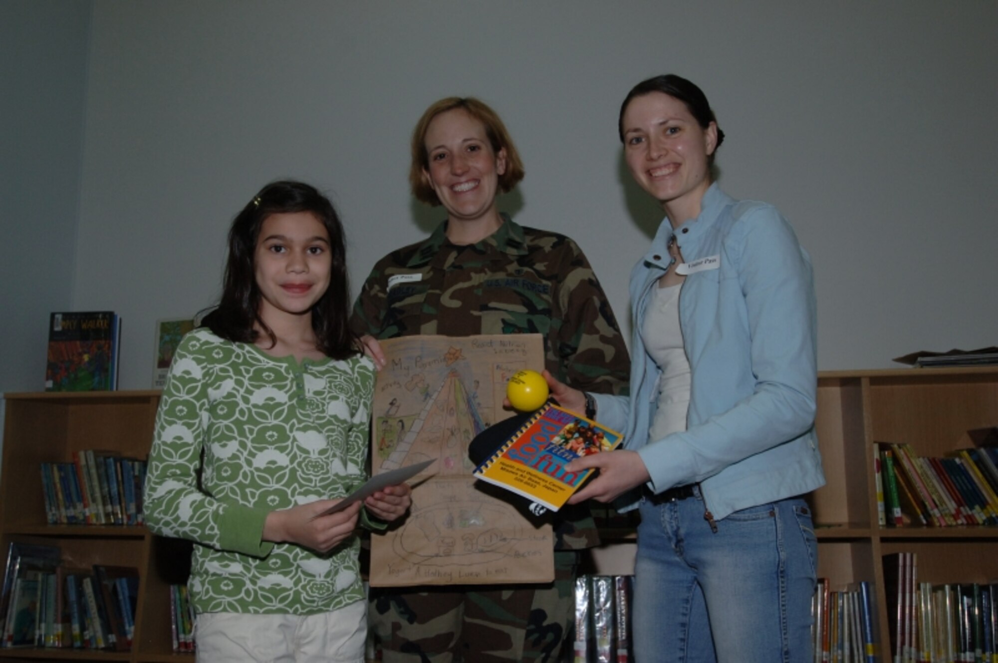 MISAWA AIR BASE, Japan -- Aviana Morales is awarded first place for third grade in the National Nutrition Month coloring contest by Capt. Jennifer Bradley of the 35th Aerospace Medicine Squadron and volunteer Christine Lyon at the Sollars Elementary school library April 3, 2008.  This is the second National Nutrition Month Misawa has held. (U.S. Air Force photo by Senior Airman Robert Barnett)