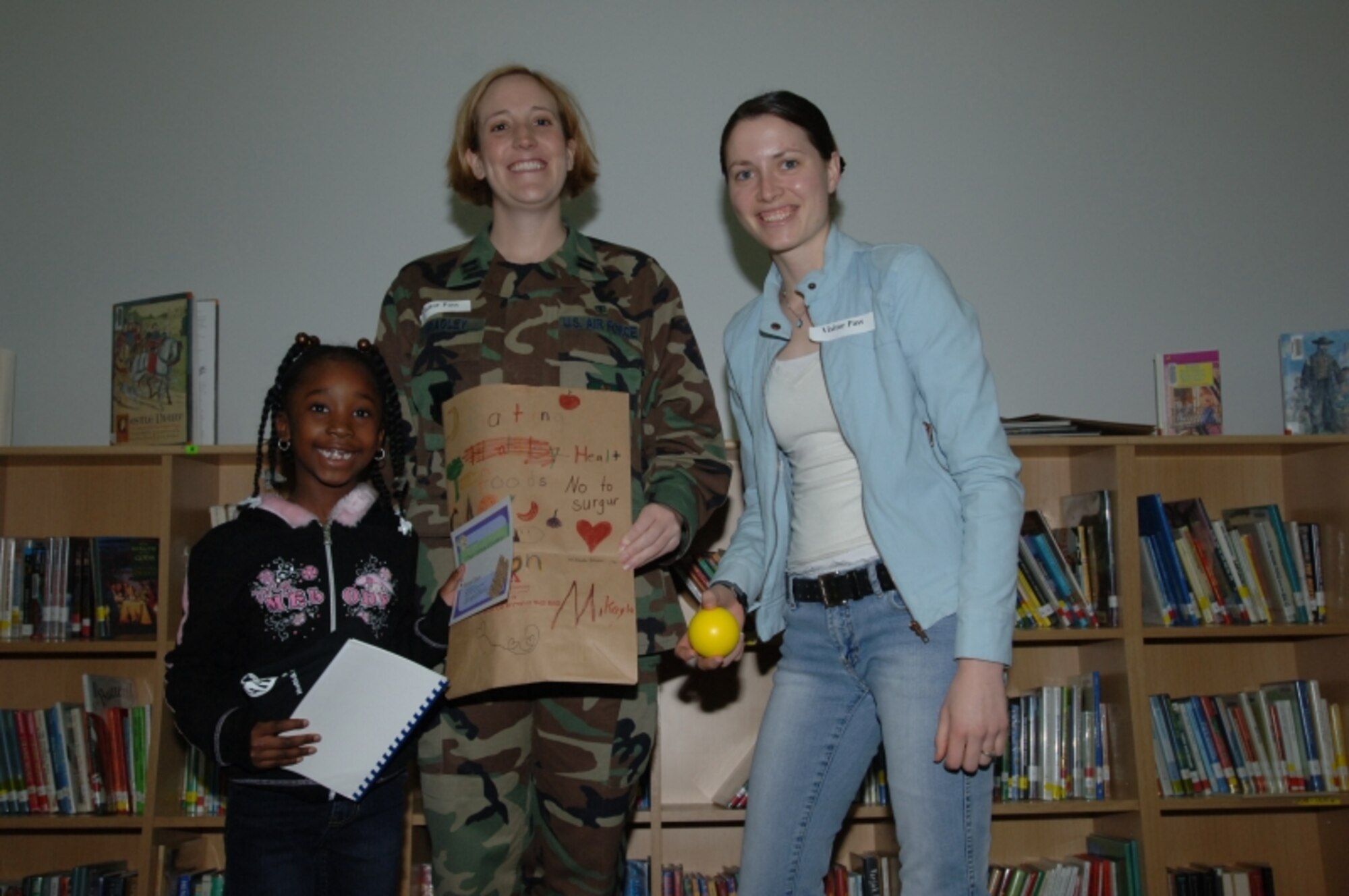 MISAWA AIR BASE, Japan -- Mikayla Eason is awarded first place for first grade in the National Nutrition Month coloring contest by Capt. Jennifer Bradley of the 35th Aerospace Medicine Squadron and volunteer Christine Lyon at the Sollars Elementary school library April 3, 2008.  The children researched for their submissions using the American Dietetic website. (U.S. Air Force photo by Senior Airman Robert Barnett)