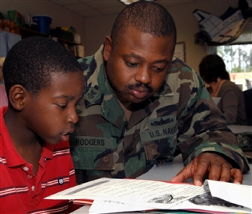 U.S. Navy Petty Officer 1st Class Marcus Rodgers helps a student at Gaston Point Elementary School in Gulfport, Miss., with his studies in the Building On Our Skills Together program, April 1, 2008. Rodgers is the armory supervisor for the 25th Naval Construction Regiment. 