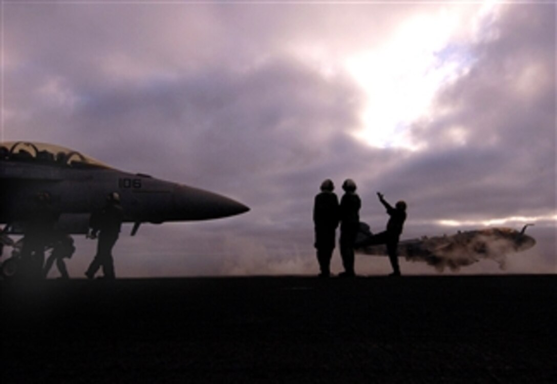 A U.S. Navy plane director positions an F/A-18F Super Hornet aircraft, left, onto a catapult as an EA-6B Prowler aircraft, right, takes off from the flight deck of the USS Ronald Reagan, which is under way in the Pacific Ocean, April 5, 2008.