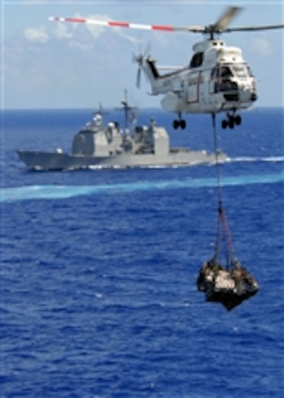 An AS-332 Super Puma helicopter from the Military Sealift Command combat stores ship USNS Niagara Falls (T-AFS 3) carries a cargo net of supplies to the aircraft carrier USS Abraham Lincoln (CVN 72) as the ships operate in the Pacific Ocean on April 5, 2008.  Behind the Super Puma is the guided-missile cruiser USS Mobile Bay (CG 53), one of the ships in the USS Abraham Lincoln Strike Group.  