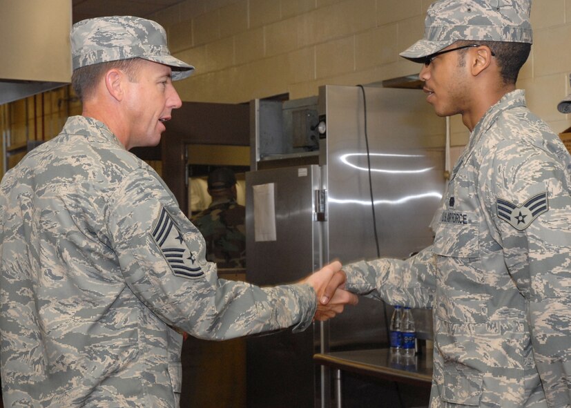 KUNSAN AIR BASE, Republic of Korea—  Chief Master Sgt. Anthony Bishop Pacific Air Forces command chief, presents Senior Airman Roderick Gillins, 8th Services Squadron dining facility manager, a coin here during his visit to the base April 7.  (U.S. Air Force Photo/Staff Sgt Araceli Alarcon) 