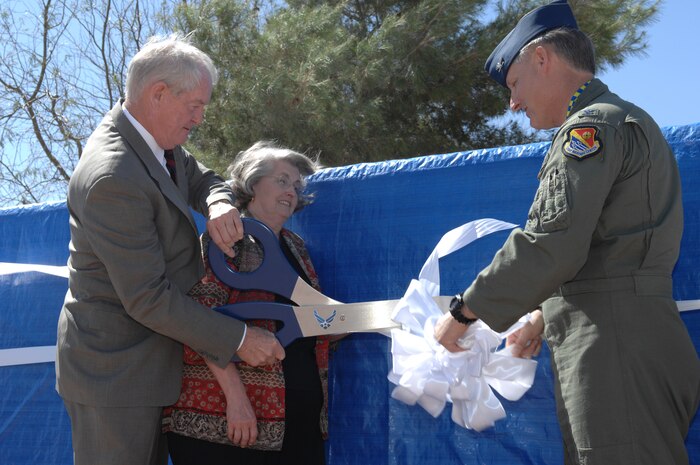 NELLIS AIR FORCE BASE, Nev. –  Maj. Gen. (Ret.) Billy and Mrs. McCoy assist Col. Michael Bartley, 99th Air Base Wing commander, with the ribbon cutting to unveil the new sign during the Environmental Grove Rededication Ceremony here April 3. The 99th Civil Engineer Squadron Environmental Office rededicated the 16-year-old grove to General McCoy in honor of his environmental commitment. (U.S. Air Force Photo/Senior Airman Larry Reid Jr.)
