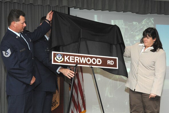 Tech. Sgt. Andy Reed, a former member of the 20th Special Operations Squadron, assists Kara Kerwood with the unveiling of a street sign named in her husband’s honor during a ceremony at the 20th SOS March 25. (U.S. Air Force photo/ Senior Airman Stephanie Jacobs) 