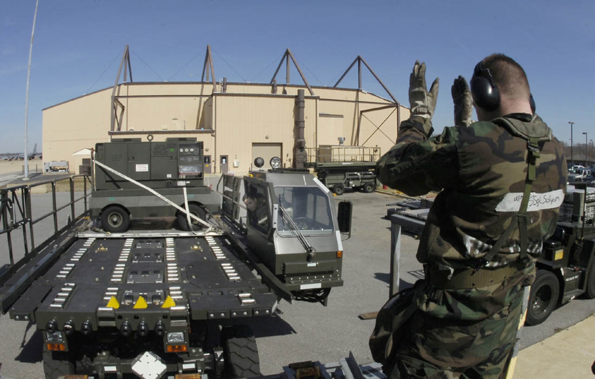 ANDREWS AIR FORCE BASE, Md. -- Staff Sgt. Michael Solyom, 69th Aerial Port Squadron air transportation journeyman, directs Senior Airman Erick O. Perez, 69th APS air transportation journeyman, who drives a next-generation small loader to line up with a highline dock. (U.S. Air Force photo/Bobby Jones)