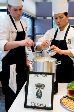 Specialists Ezekiel Ruckle and Jiao Tengbo, Soliders with the 1st Special Forces Group at Fort Lewis, add ingredients to their award-winning clam chowder during the presentation portion of the competition. (U.S. Air Force photo/Abner Guzman) 