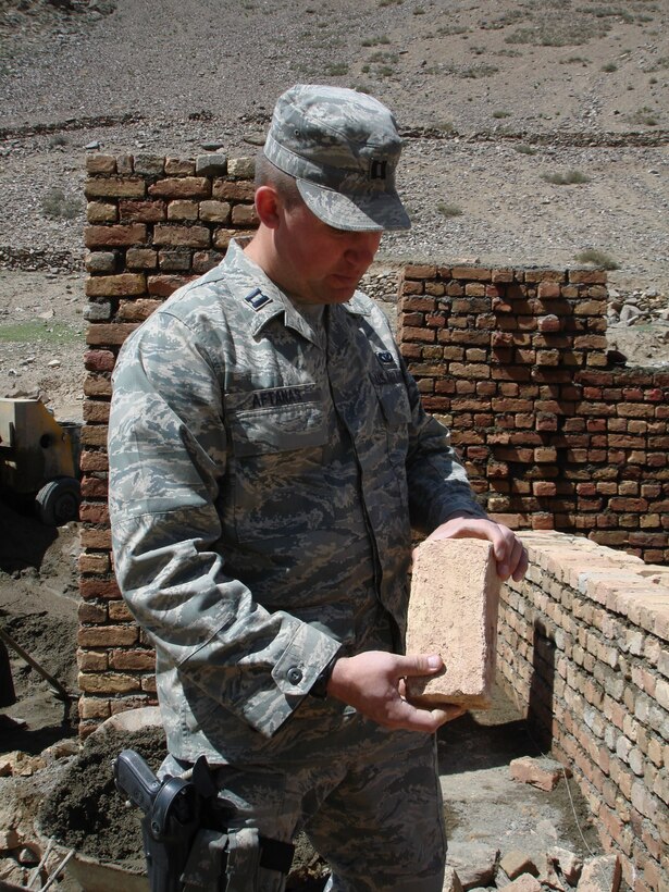 PANJSHIR, Afghanistan -- Capt. Jason M. Aftanas, Panjshir Provincial Reconstruction Team engineer, inspects a brick for the wall for a tashnab (bathroom) at the Pukh High School construction site April 1. Pukh High School is a two-story, 16-room, reinforced concrete structure that will accommodate up to 3,000 students. (U.S. Air Force photo by Capt. Jillian Torango)