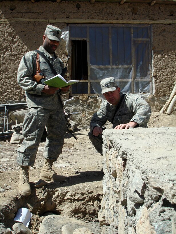 Capt. Jason M. Aftanas, Panjshir Provincial Reconstruction Team engineer, takes an initial look at a foundation for a schoolbook repository and passes along the information to his partner, Capt. Kenneth McGinnis at the site near the Khenj District Center April 1.  (U.S. Air Force photo by Capt. Jillian Torango)