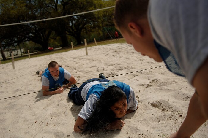 Xochiquetzal Baldwin and Matthew Baldyga crawl through sand while Daniel Graham cheers them on at the picnic grounds April 4. The 437th Medical Group hosted this month's Commander's Fitness Challenge that tested teams on various self-aid buddy care activities and finished with a race. The 15th Airlift Squadron won the golden crutch for finishing with the best time. Baldwin, Baldyga and Graham are all with the 437th Communications Squadron.  (U.S. Air Force photo/Senior Airman Nicholas Pilch)