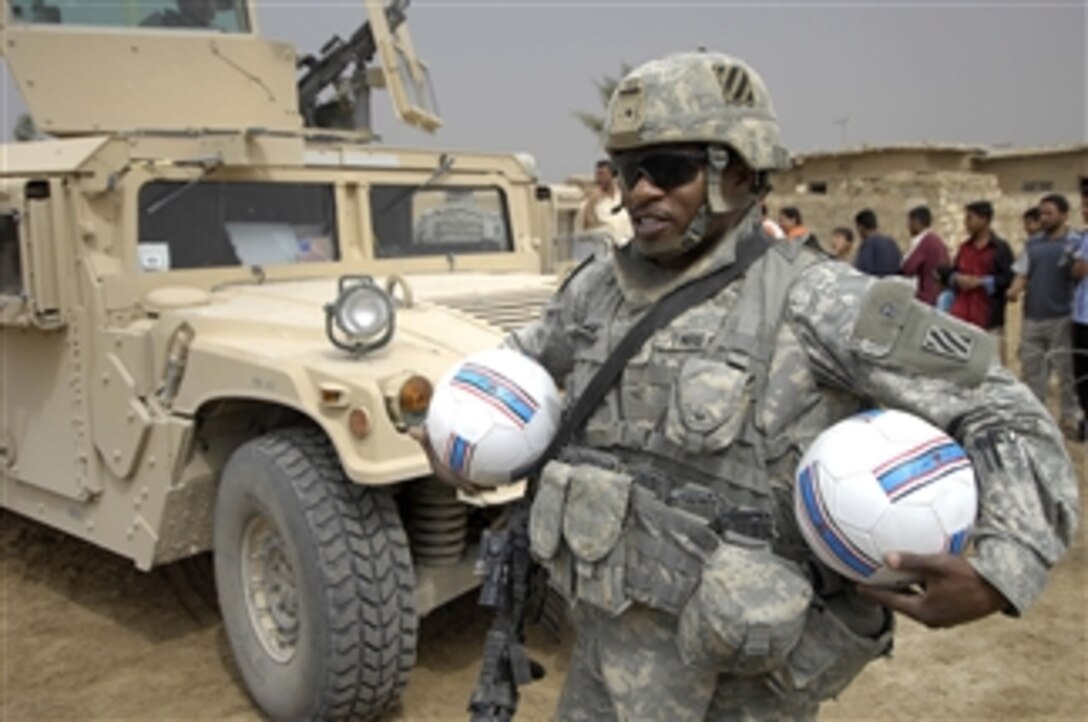 U.S. Army Staff Sgt. Derrick Threatt prepares to hand out soccer balls to children during a medical operation in Sabah Nissan, Iraq, on March 27, 2008.  Threatt is attached to Alpha Battery, 1st Battalion, 10th Field Artillery, 3rd Infantry Division.  