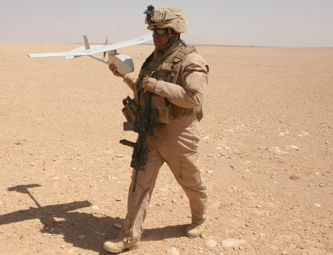 Cpl. Luis E. Piris-Santiago, a scout team leader and Unmanned Air Vehicle operator with Charlie Company, 2nd Light Armored Reconnaissance Battalion, Regimental Combat Team 5, carries the Raven after a successful landing during a systems test in western Anbar province, Iraq, April 8. The Raven is a UAV that provides real-time video imagery of the battlefield. The plane is controlled by an operator using a remote with vision display and knobs like a video game device.