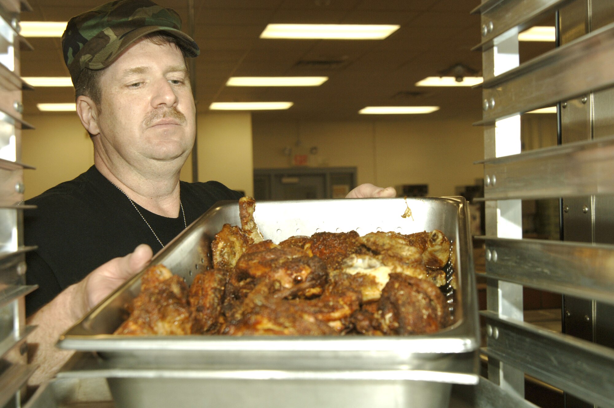 VOLK FIELD AIR NATIONAL GUARD BASE, Wis. -- Master Sgt. Jamie Kuzio, from the 134th Services Squadron, pulls out a pot of baked chicken to put on the serving line, Apr. 1, at Volk Field during an exercise.  Members at the exercise ate meals ready to eat for the first few days until the dining facility set up to cook hot meals.  The dining facility was up and ready for business 14 hours earlier than the required scheduled time. (Photo by Tech. Sgt. Chyrece Campbell)