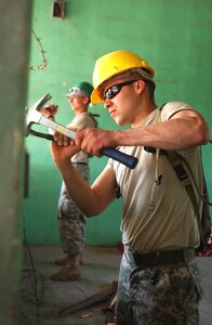 LAS MESAS, Honduras - Sgt. Juan M. Ozuna from the 672nd Engineer Company repairs a dilapidated schoolhouse during their Annual Training. U.S. Army engineers are among the personnel participating in Beyond the Horizon, a training exercise that provides infrastructure renovation, as well as basic medical and dental care, to rural areas of this Central American country. Soldiers working in Las Mesas will replace the school's doors and windows, repair the roof, and repaint the entire structure, in addition to improving a soccer field on which local children play. (Photo by Sgt. Claude W. Flowers, 304th Public Affairs Detachment.)
