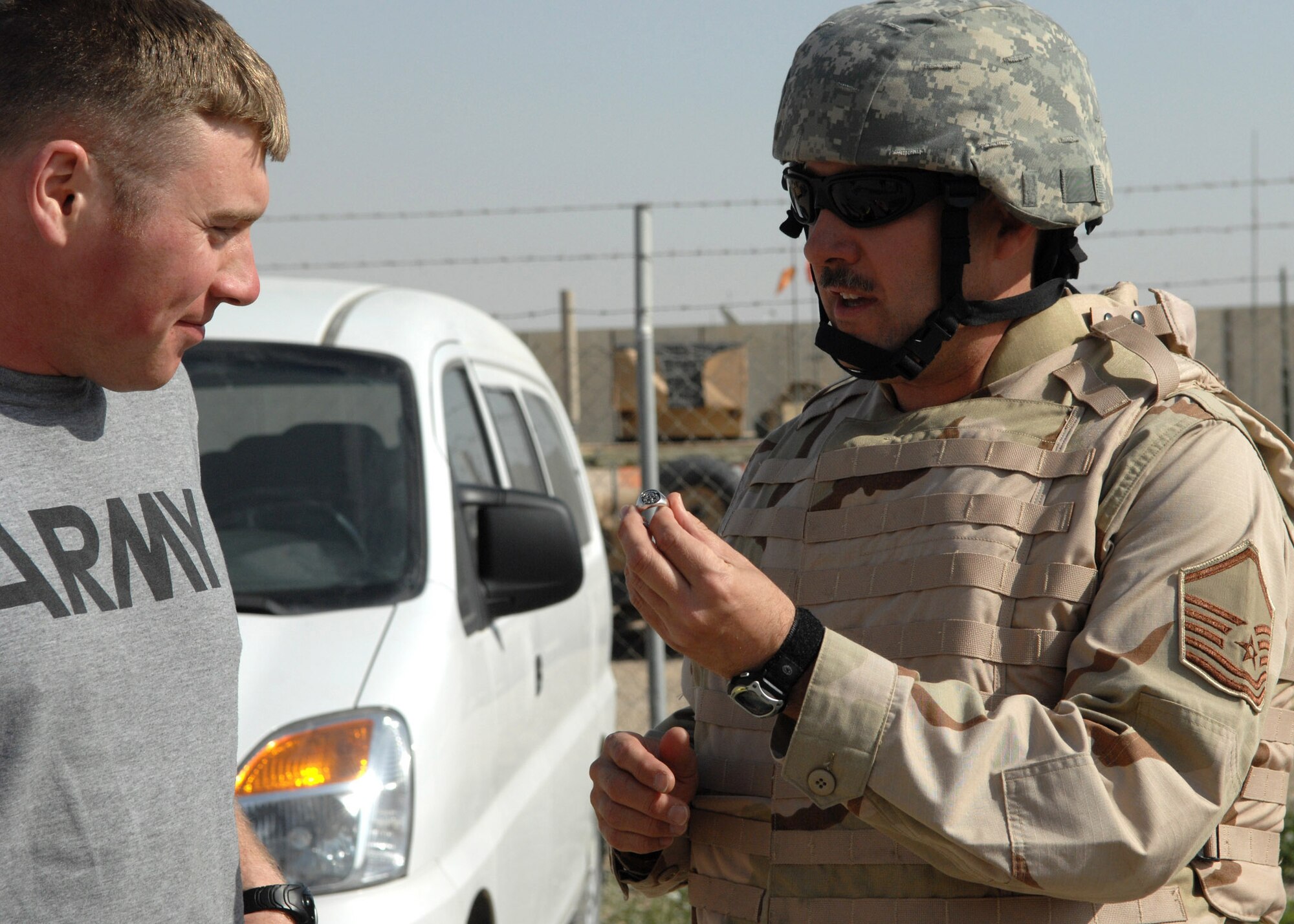 Master Sgt. Dean Smith (right), trombonist with U.S. Air Forces Central Band, presents a family ring to Army Specialist David Smith, a vehicle operator with the U.S. Army's 1st Brigade, 10th Mountain Division. Sergeant Smith re-united with his deployed son during the band's recent visit to Kirkuk. (U.S. Air Force photo by Senior Airman SerMae Lampkin) 
