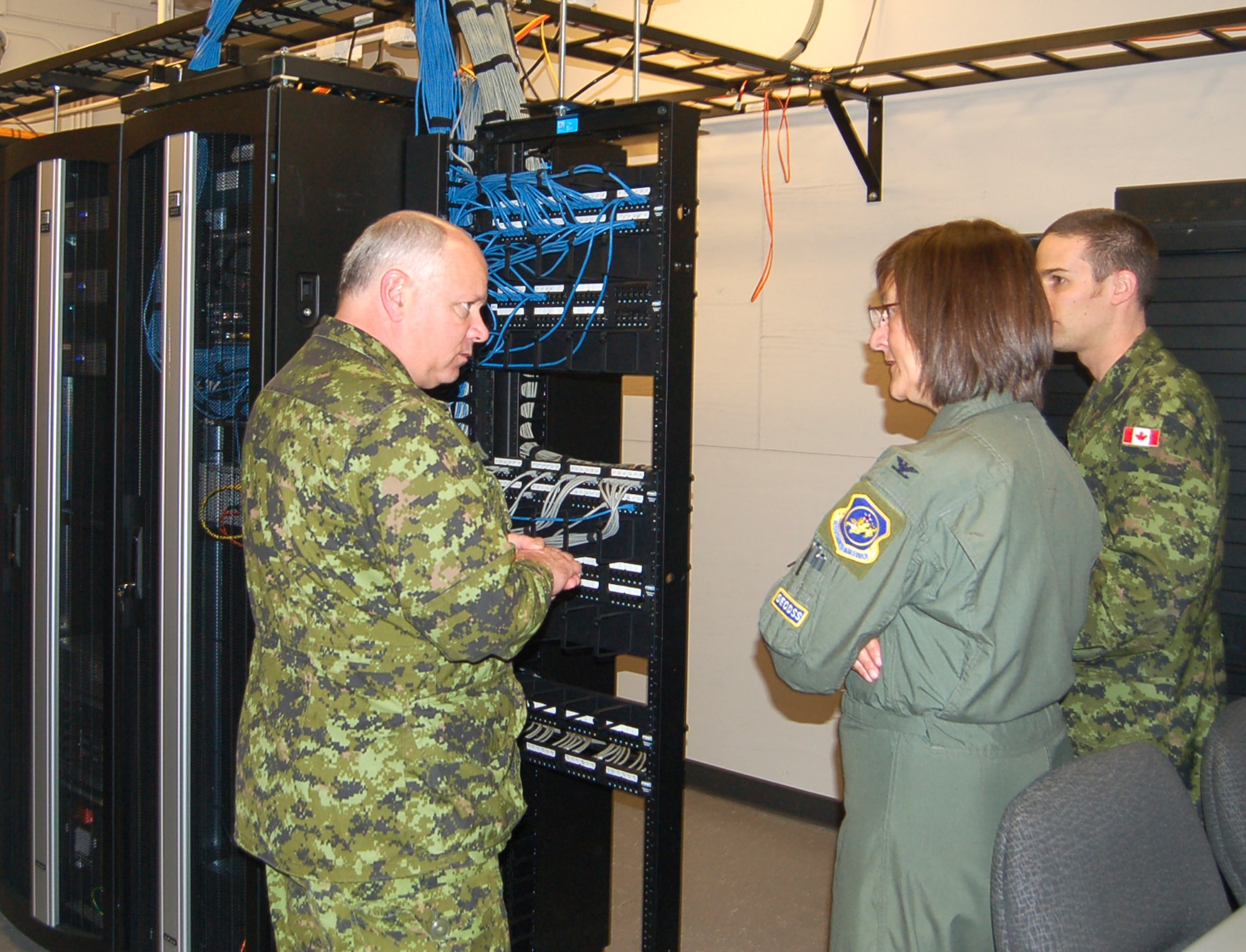 Lt. Gen. Charlie Bouchard, North American Aerospace Defense Command deputy commander, and Capt. Olivier Montplaisir explain the Canadian Forces’ computer network to Col. Liz Anderson, individual mobilization augmentee to the 21st Space Wing commander. The Canadian Forces Support Unit moved into its new office space in Building 365 this month, giving the servicemembers more room for their personnel support services and computer networks. The project cost roughly $500,000, funded exclusively by the 21st SW. (U.S. Air Force photo/Corey Dahl)
